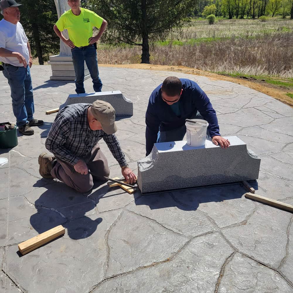 Workers assemble the granite benches at the memorial site